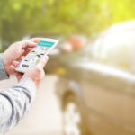 Man holding phone looking at rideshare app with a car in background